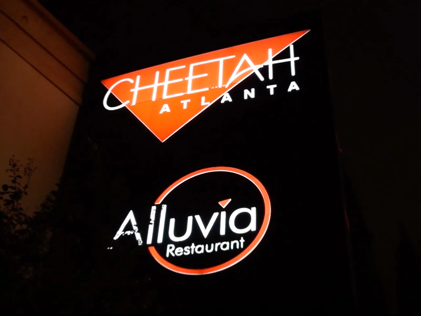 Illuminated Cheetah Atlanta and Alluvia Restaurant sign at night