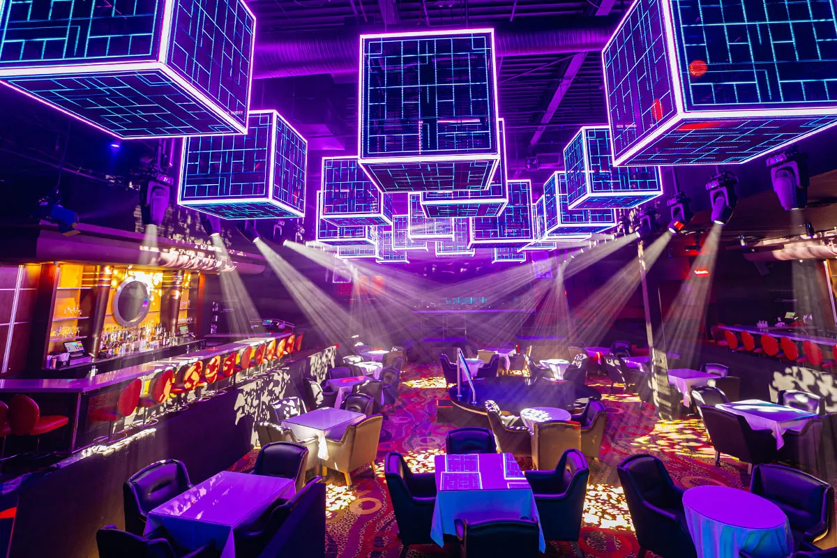 Empty main room at The Cheetah with suspended neon cube lighting over tables and the stage