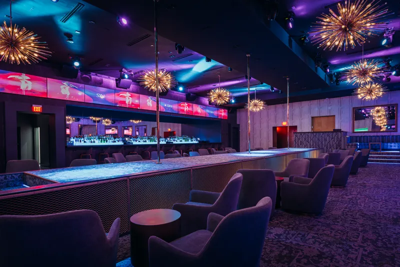 SYN main room with lounge chairs along the stage under starburst chandeliers