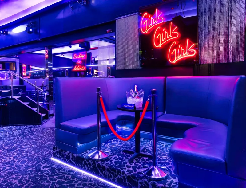 Reserved booth with champagne on ice beside neon signs at Tattletale Lounge