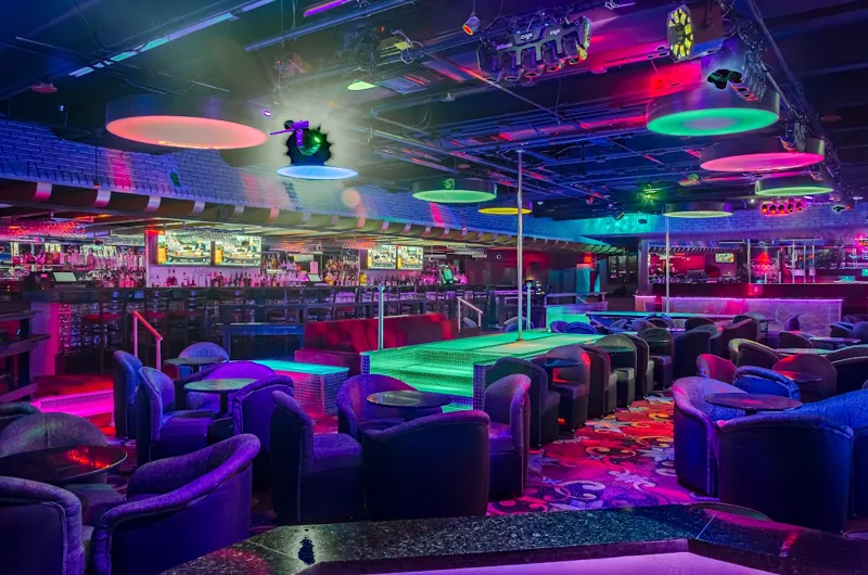 Empty main room at Booby Trap on the River with lit stage, lounge chairs and bar